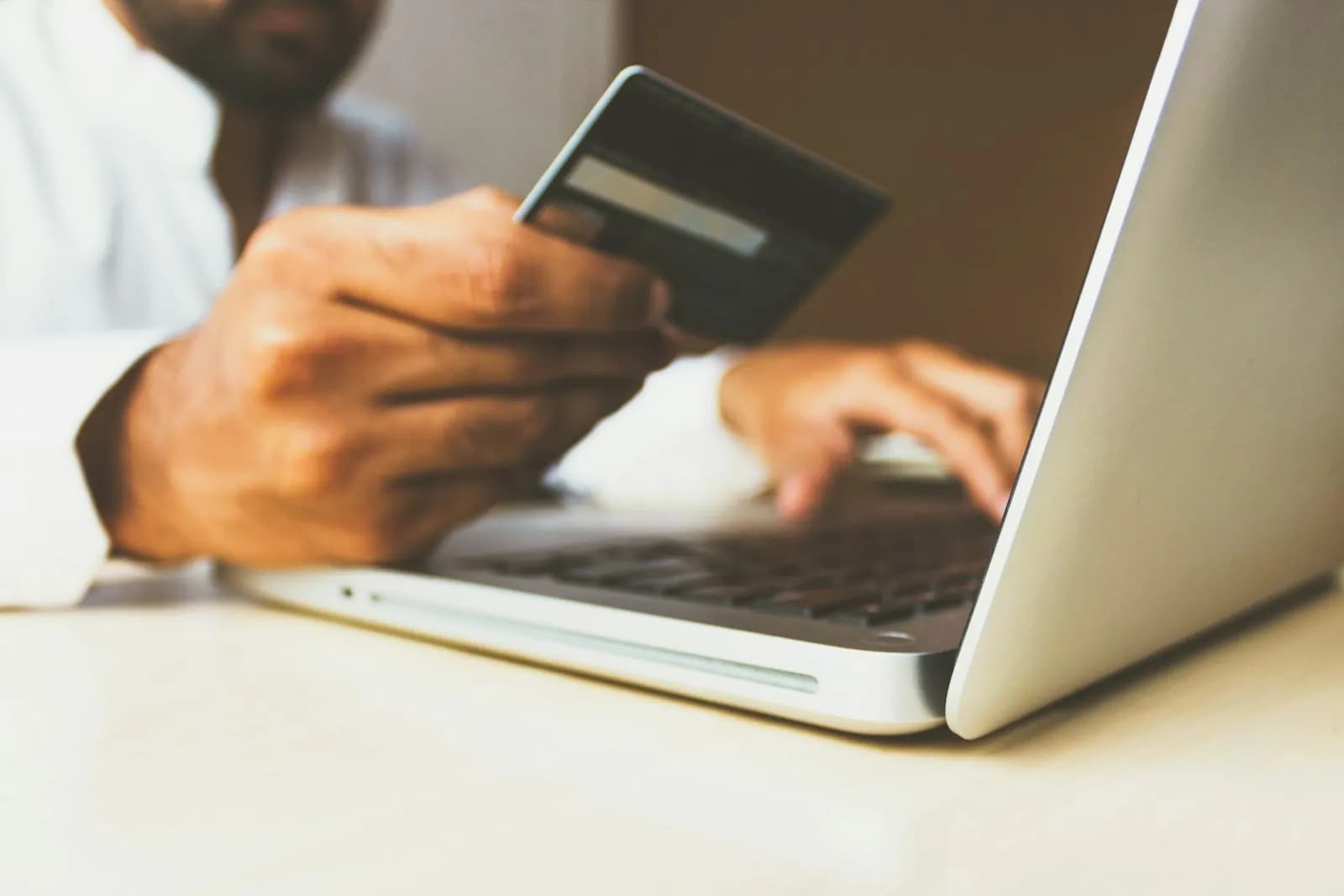 person using laptop computer holding card — illustrating What is Google's Universal Commerce Protocol (UCP) and does your WooCommerce store need it?