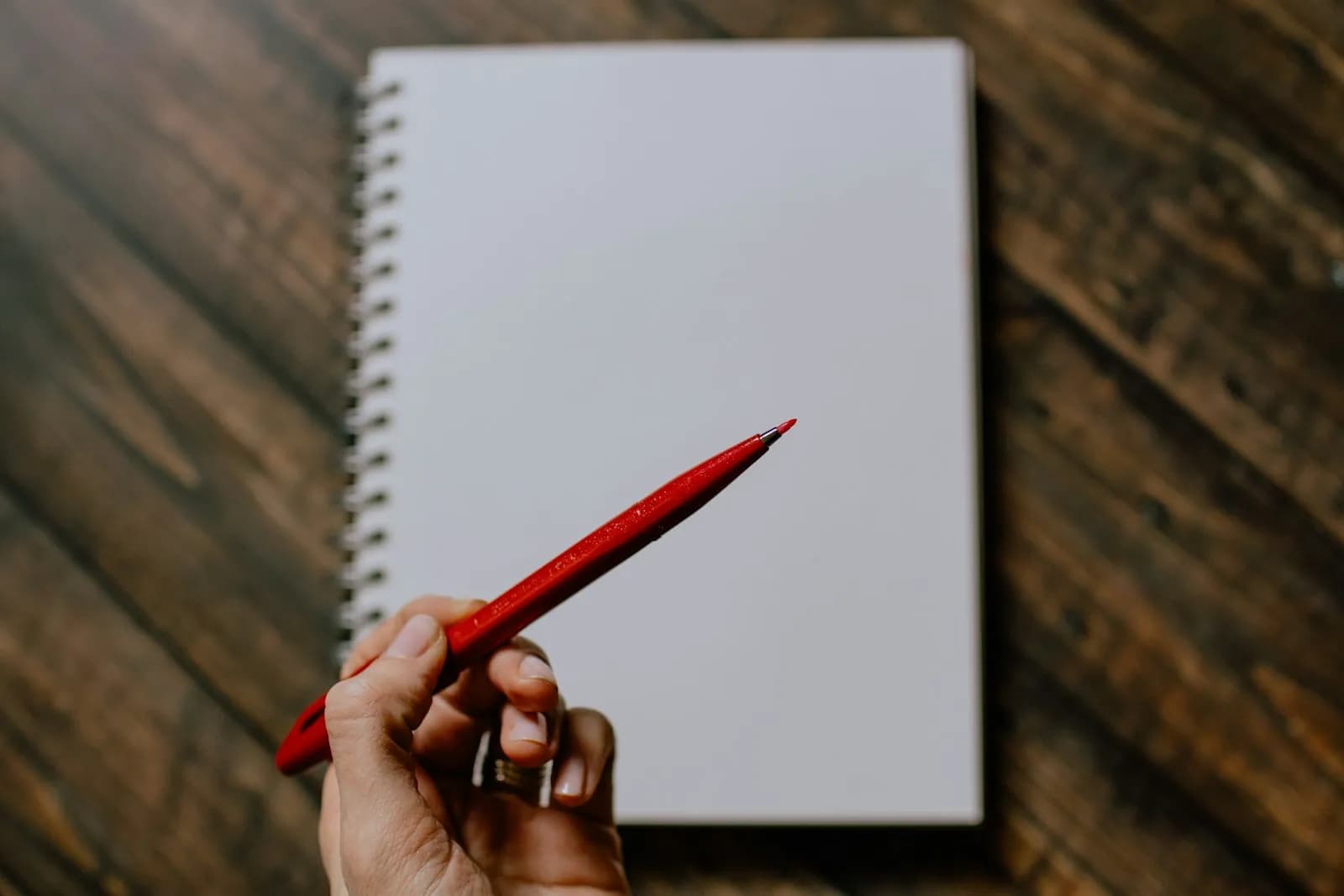 person holding red pencil writing on white paper — illustrating GEO vs SEO: what actually changes in how you write